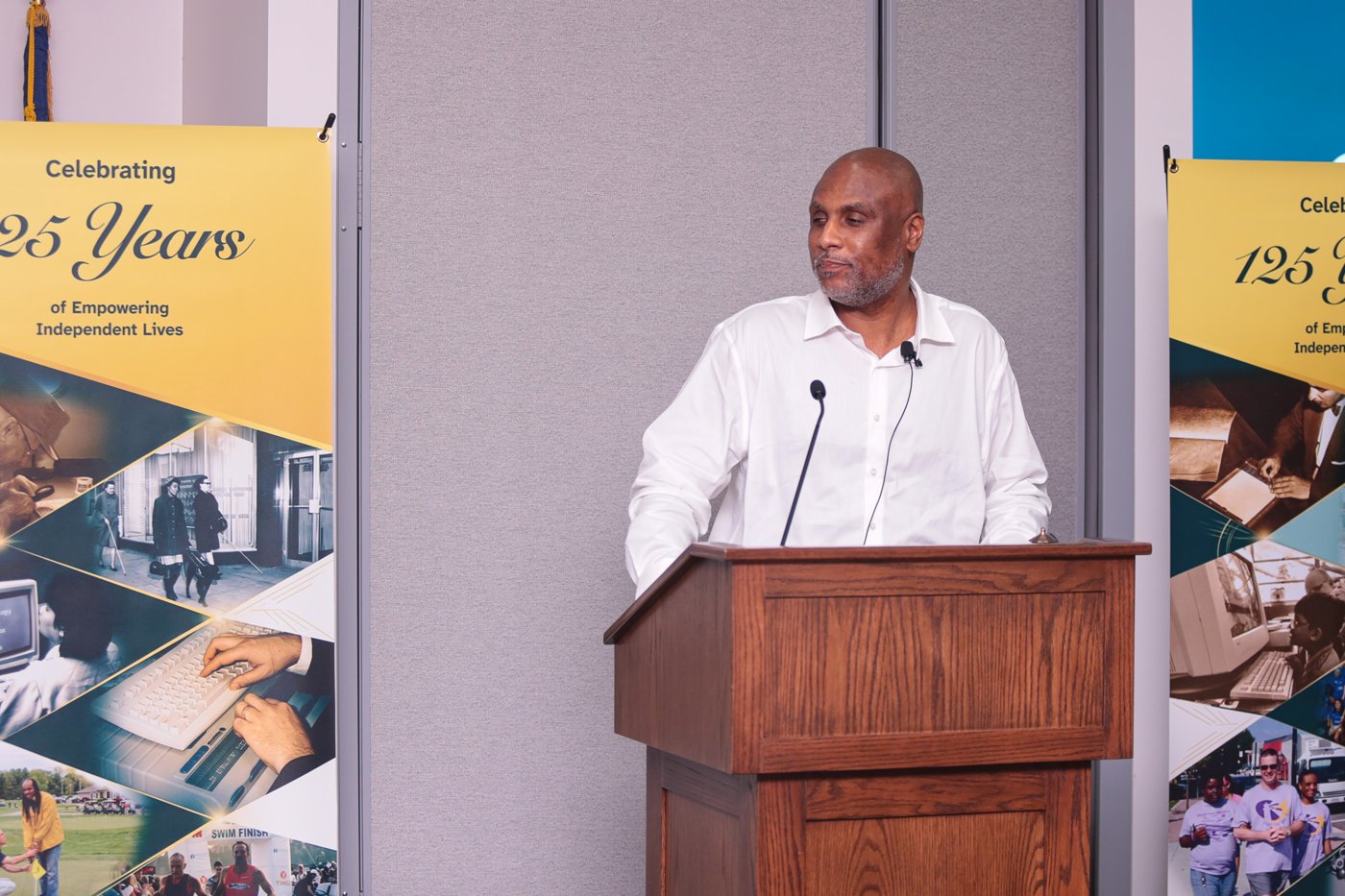 Board member Shawn Callaway, who emceed the evening, speaks at the podium beside the Celebrating 125 Years banners.
