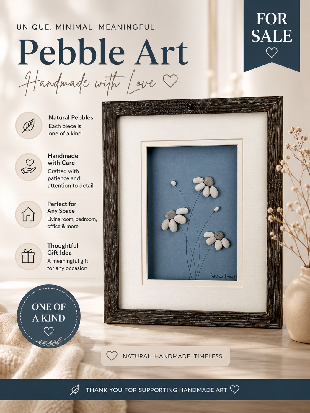 Framed pebble art of white daisy flowers on thin stems against a navy blue background.