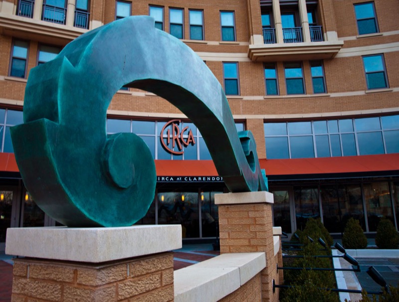 Large teal sculpture in front of Circa restaurant's brick and glass building exterior.