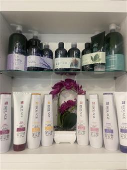 Shelves of salon hair-care products including shampoo, conditioner, and Biolage treatment tubes.